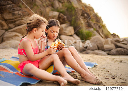 Children eating snack on beach during summer vacation 139777394