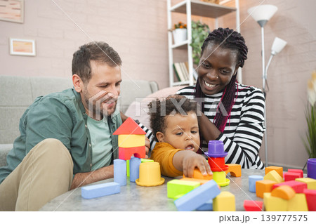 Family playing with colorful blocks in a cozy living room together Family playing with colorful blocks in a cozy living room together 139777575