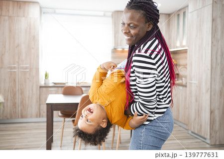 Happy multiracial family playing together in their kitchen at home Happy multiracial family playing together in their kitchen at home 139777631