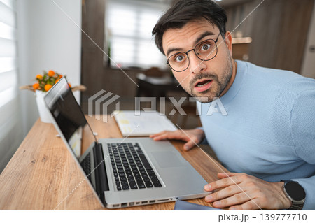 Portrait of surprised man looking at camera while sitting at desk Portrait of surprised man looking at camera while sitting at desk 139777710