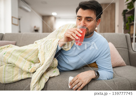 Sick man lies covered and drinks vitamins Sick man lies covered and drinks vitamins 139777745