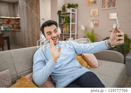 Man with wireless headphones talking on a video call at home 139777760