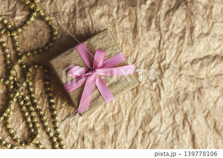 Golden gift box with pink bow on the gold background. Holiday concept. Golden gift box with pink bow on the gold background. Holiday concept. 139778106