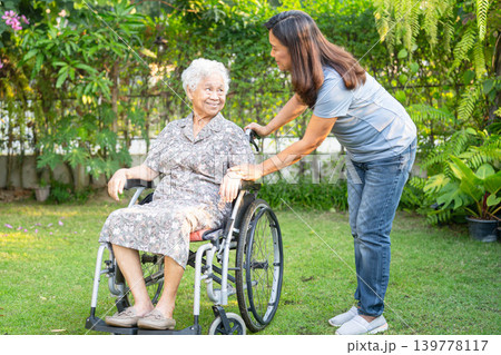 Asian elderly woman disability patient sitting on wheelchair in park. Asian elderly woman disability patient sitting on wheelchair in park. 139778117