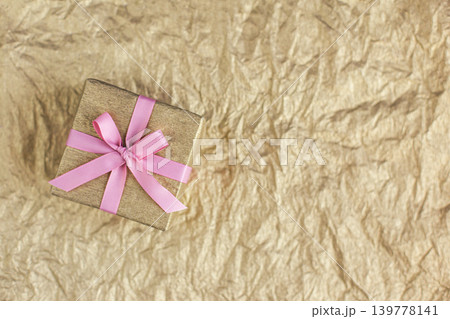 Golden gift box with pink bow on the gold background. Holiday concept. Golden gift box with pink bow on the gold background. Holiday concept. 139778141