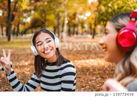 Friends enjoying music together in an autumn park filled with colorful leaves 139778439