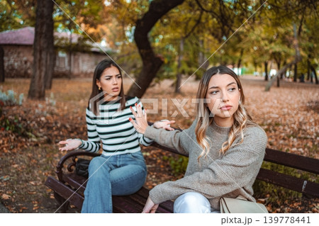 Two girls share an autumn moment of disagreement in a park setting 139778441