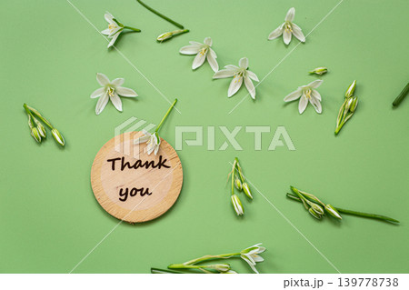 Delicate white flowers and wooden thank you sign on green surface Delicate white flowers and wooden thank you sign on green surface 139778738