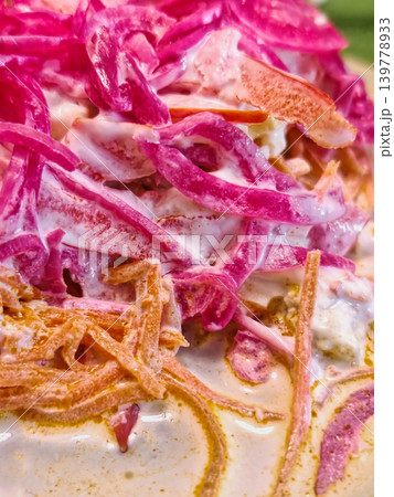 Sliced carrots and onions prepare with creamy sauce at a food stall in a bustling market during the day. People gather around to enjoy the dish Sliced carrots and onions prepare with creamy sauce at a food stall in a bustling market during the day. People gather around to enjoy the dish 139778933