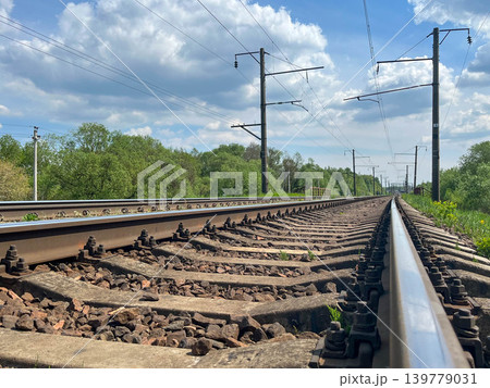 Railway tracks stretching into distance with electric infrastructure under dramatic cloudy sky 139779031