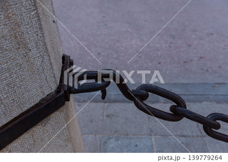 Black metal chain tied to a stone pylon 139779264
