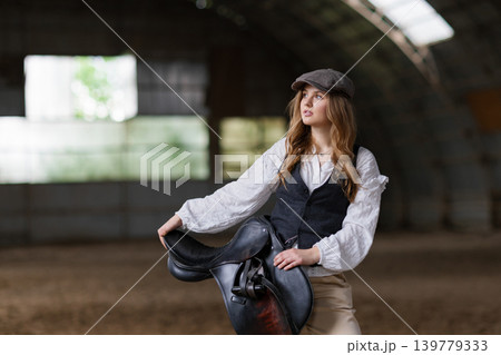 Young woman posing holding equestrian horse saddle 139779333