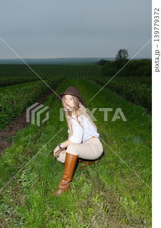 Woman smiling wearing hat and boots in field Woman smiling wearing hat and boots in field 139779372