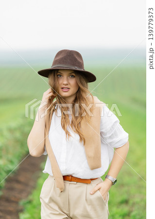 Woman in hat smiling while walking outdoors 139779373