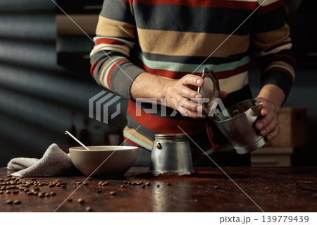 A man in a striped jumper is about to make coffee in an old Italian coffee maker. A man in a striped jumper is about to make coffee in an old Italian coffee maker. 139779439