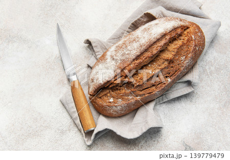 Homemade sourdough rye bread with knife on linen Homemade sourdough rye bread with knife on linen 139779479