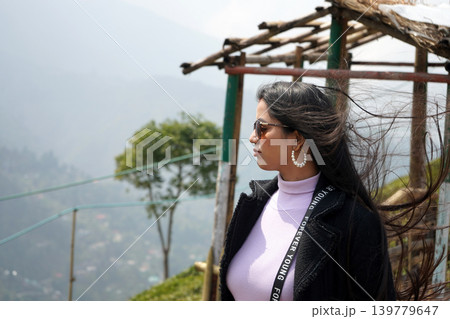 Elegant woman with windblown hair looking away on a foggy mountain overlook at Darjeeling 139779647