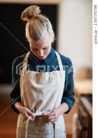 Chef, woman and tie apron in kitchen, restaurant or catering service at hotel for gastronomy. Uniform, cooking and person with knot on clothes, culinary or preparation of professional waitress at job 139779796
