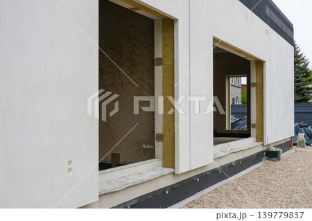 Modular prefab house facade with exposed insulation layer and SIP panel window openings detail 139779837