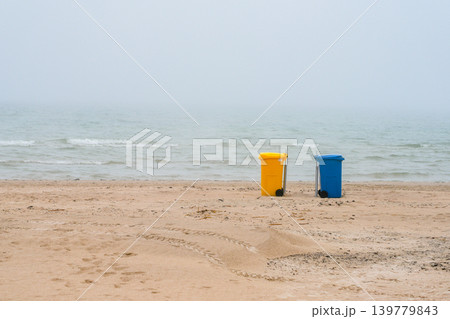 Colorful recycling bins on foggy Baltic Sea beach during calm misty morning in Latvia coastline 139779843