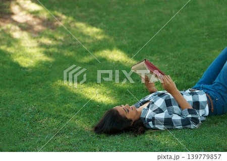 Woman, knowledge and reading book on grass, literature and smiling for fiction or fantasy story. Female person, nature and relaxing on lawn for education, information and student studying in garden Woman, knowledge and reading book on grass, literature and smiling for fiction or fantasy story. Female person, nature and relaxing on lawn for education, information and student studying in garden 139779857
