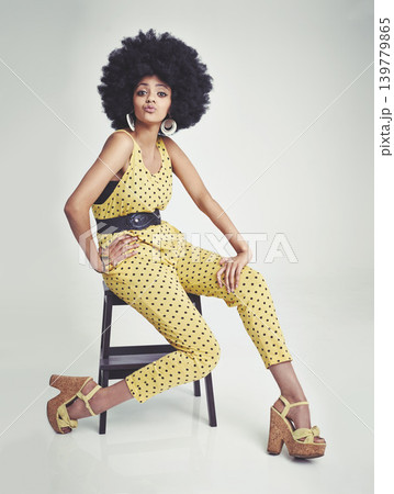 Black woman, portrait and relax on chair in fashion, yellow jumpsuit or high heels on a gray studio background. African female person with afro, makeup or jewelry in beauty or style on mockup space Black woman, portrait and relax on chair in fashion, yellow jumpsuit or high heels on a gray studio background. African female person with afro, makeup or jewelry in beauty or style on mockup space 139779865