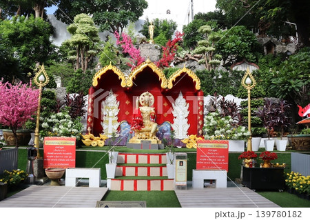 Thai Buddhist Shrine with Golden Buddha and Floral Arrangements Thai Buddhist Shrine with Golden Buddha and Floral Arrangements 139780182