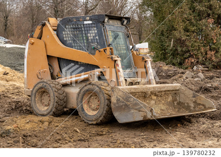 Bobcat excavator performs earthmoving tasks at a construction site on a cold winter day in a rural setting with surrounding trees 139780232