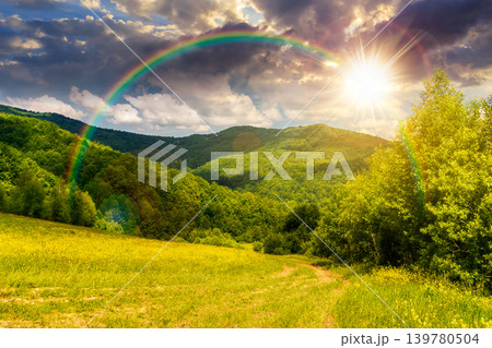 sunset over beautiful countryside of ukraine. wonderful view of summertime landscape in mountains. trail through the grassy field near forested rolling hills. rural scenery. weather with rainbow sunset over beautiful countryside of ukraine. wonderful view of summertime landscape in mountains. trail through the grassy field near forested rolling hills. rural scenery. weather with rainbow 139780504