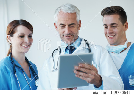 Tablet, discussion and doctor with nurses in hospital for medical diagnosis or treatment meeting. Team, digital technology and senior surgeon talk to healthcare workers for surgery research in clinic Tablet, discussion and doctor with nurses in hospital for medical diagnosis or treatment meeting. Team, digital technology and senior surgeon talk to healthcare workers for surgery research in clinic 139780641