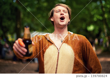 Man, outdoor and cheers with beer to drink, toast and happy celebration in bear outfit. Animal, suit and person smile in forest with lager, bottle and drunk from drinking alcohol in park or woods 139780824