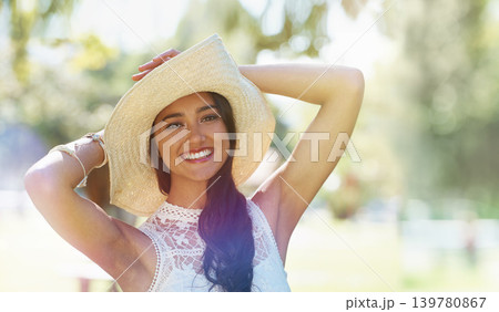 Woman, portrait and hat for relaxing in park or garden, smiling and joyful on summer holiday. Female person, peace and enjoy vacation in countryside, outdoors and calm on weekend adventure in nature 139780867