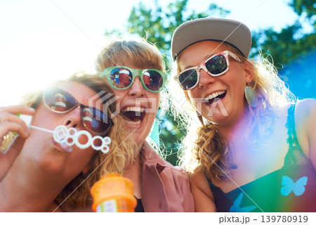 Women, friends and bubbles for blowing or fun outdoor with sunglasses on weekend, break and holiday for relax. People, happy and plastic wand or toy for playing or laughing with vacation or adventure Women, friends and bubbles for blowing or fun outdoor with sunglasses on weekend, break and holiday for relax. People, happy and plastic wand or toy for playing or laughing with vacation or adventure 139780919