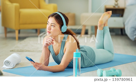 Smartphone, yoga and headphones of woman typing on chat app for fitness communication, social media update or blog writing wellness. Pilates girl with exercise gear and technology in home living room 139780961
