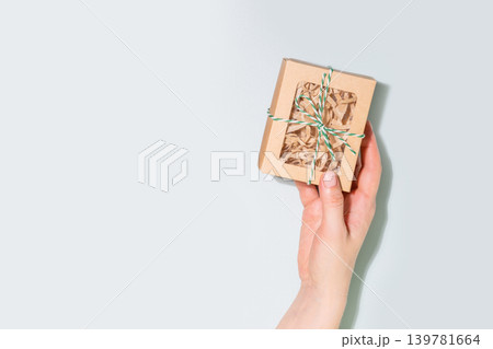 Hand Holding Christmas Gift Box Wrapped In Craft Paper With Green Twine Hand Holding Christmas Gift Box Wrapped In Craft Paper With Green Twine 139781664