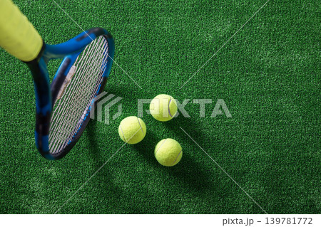 Tennis racket and balls on green artificial grass with copy space Tennis racket and balls on green artificial grass with copy space 139781772