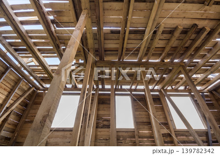 New wooden house under construction. Close-up of walls and ceiling frame with windows openings from inside. Ecological dream home of natural materials. Building, construction and renovation concept. 139782342