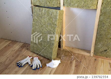 Rock wool and fiberglass insulation staff material for cold barrier. Tools for work with glass wool: protective goggles, glasses and mask. Warm home, economy, construction and renovation concept. 139782354