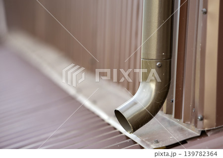 Close-up of brown new gutter metal system pipe on wall. Drain protection, professional work concept. Close-up of brown new gutter metal system pipe on wall. Drain protection, professional work concept. 139782364