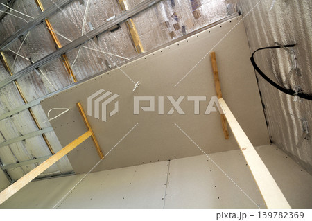 Room under construction with silver aluminum insulation foil and drywall on walls and ceiling. 139782369