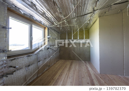 Room under construction with silver aluminum insulation foil and drywall on walls and ceiling. Room under construction with silver aluminum insulation foil and drywall on walls and ceiling. 139782370