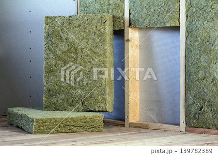 Wooden frame for future walls with drywall plates insulated with rock wool and fiberglass insulation staff for cold barrier. Comfortable warm home, economy, construction and renovation concept. Wooden frame for future walls with drywall plates insulated with rock wool and fiberglass insulation staff for cold barrier. Comfortable warm home, economy, construction and renovation concept. 139782389