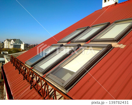 Red tiled house roof with attic windows. Roofing construction, window installation, modern architecture concept. Red tiled house roof with attic windows. Roofing construction, window installation, modern architecture concept. 139782431