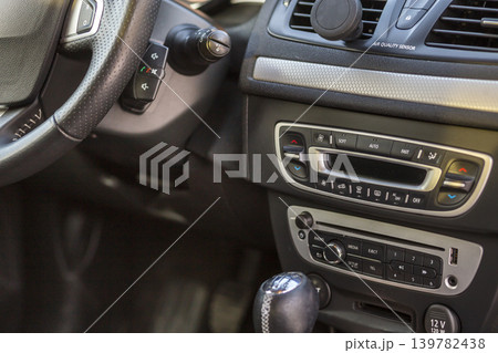 Luxurious car black leather interior. Close-up detail of handbrake manual brake and gearshift stick on blurred dashboard background. Transportation, design, modern technology concept. Luxurious car black leather interior. Close-up detail of handbrake manual brake and gearshift stick on blurred dashboard background. Transportation, design, modern technology concept. 139782438