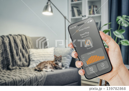 Female hand holding smartphone with smart home application interface showing energy monitoring statistics 139782868