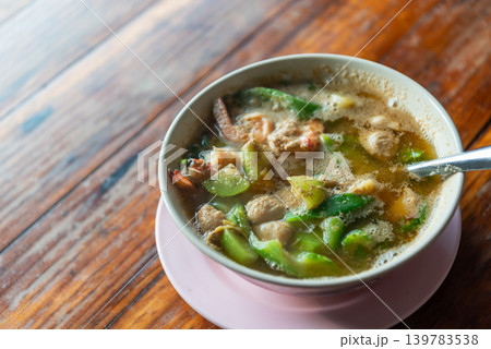 Traditional Thai kaeng liang soup shrimp mixed vegetables herbs served hot in bowl on wooden table healthy local cuisine 139783538