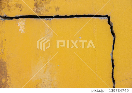 Full frame shot of cracked yellow wall. Wider cracks often represent serious structural damage and can cause serious issues. 139784749