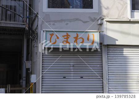 シャッターの降りたひまわりと書かれた看板が残る店舗の外観 139785328