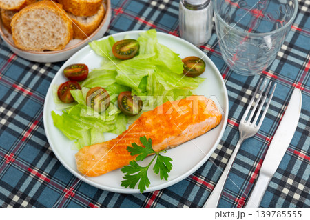 Delicious meal of seared salmon with lettuce and tomatoes salad Delicious meal of seared salmon with lettuce and tomatoes salad 139785555