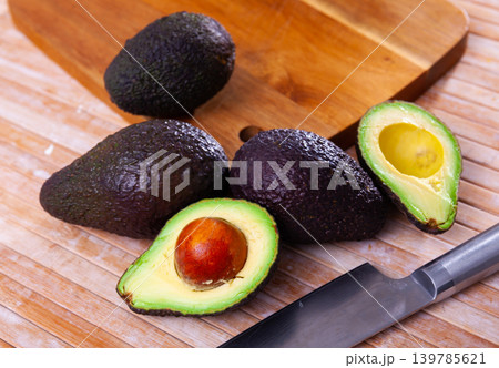 Whole and cut in half avocados on wooden background 139785621